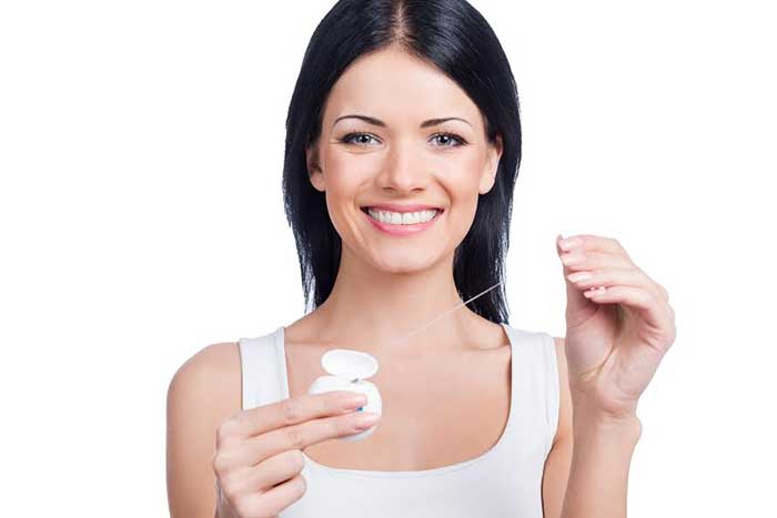 woman smiling while flossing